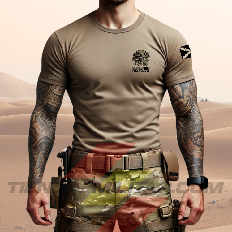 Hombre de frente con camiseta táctica color arena de Depredador Hispano en un entorno desértico. En el pecho lleva un logotipo con calavera táctica y casco, y en la espalda la frase “AQUÍ SE HABLA ESPAÑOL” junto a un fusil sobre fondo de Cruz de Borgoña. Ropa militar de alto rendimiento con diseño hispano.