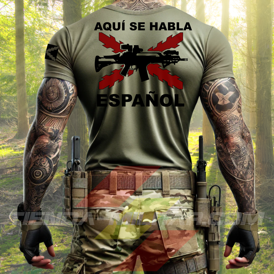 Hombre de espaldas con camiseta táctica color verde militar de Depredador Hispano en un entorno desértico. En el pecho lleva un logotipo con calavera táctica y casco, y en la espalda la frase “AQUÍ SE HABLA ESPAÑOL” junto a un fusil sobre fondo de Cruz de Borgoña. Ropa militar de alto rendimiento con diseño hispano.