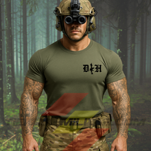 Cargar imagen en el visor de la galería, Hombre de frente con camiseta táctica fabricada en algodón, en color verde militar de la marca Depredador Hispano en un entorno nocturno y boscoso. En el pecho lleva un logotipo con con las iniciales de la marca (DH) y un fusil de asalto G36 en vertical. Ropa militar de alto rendimiento con diseño reivindicativo de poder hispano.
