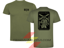 Cargar imagen en el visor de la galería, Camiseta táctica de algodón premium, color verde militar de la marca Depredador Hispano. En el pecho lleva un logotipo con con las iniciales (DH) y un fusil de asalto G36 en vertical. En la espalda la frase “TIEMPOS DUROS, HOMBRES FUERTES”. Ropa militar de alto rendimiento con diseño reivindicativo de poder hispano.
