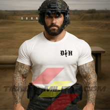 Cargar imagen en el visor de la galería, Hombre de frente con camiseta táctica fabricada en algodón, en color blanca de la marca Depredador Hispano, al fondo se puede apreciar que esta en un campo de tiro. En el pecho lleva un logotipo con con las iniciales de la marca (DH) y un fusil de asalto G36 en vertical. Ropa militar de alto rendimiento con diseño reivindicativo de poder hispano.
