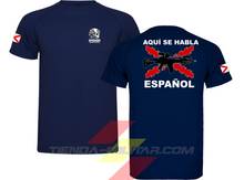 Cargar imagen en el visor de la galería, Camiseta táctica color azul marino de Depredador Hispano en un entorno desértico. En el pecho lleva un logotipo con calavera táctica y casco, y en la espalda la frase “AQUÍ SE HABLA ESPAÑOL” junto a un fusil sobre fondo de Cruz de Borgoña. Ropa militar de alto rendimiento con diseño hispano.
