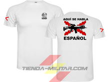Cargar imagen en el visor de la galería, Camiseta táctica color blanco de Depredador Hispano en un entorno desértico. En el pecho lleva un logotipo con calavera táctica y casco, y en la espalda la frase “AQUÍ SE HABLA ESPAÑOL” junto a un fusil sobre fondo de Cruz de Borgoña. Ropa militar de alto rendimiento con diseño hispano.
