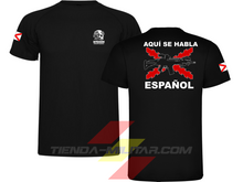 Cargar imagen en el visor de la galería, Camiseta táctica color negro de Depredador Hispano en un entorno desértico. En el pecho lleva un logotipo con calavera táctica y casco, y en la espalda la frase “AQUÍ SE HABLA ESPAÑOL” junto a un fusil sobre fondo de Cruz de Borgoña. Ropa militar de alto rendimiento con diseño hispano.
